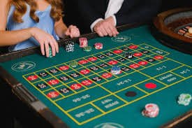 Dealer poker profesional di studio live api gacor dengan kartu dan chip di hadapan pemain di layar ponsel